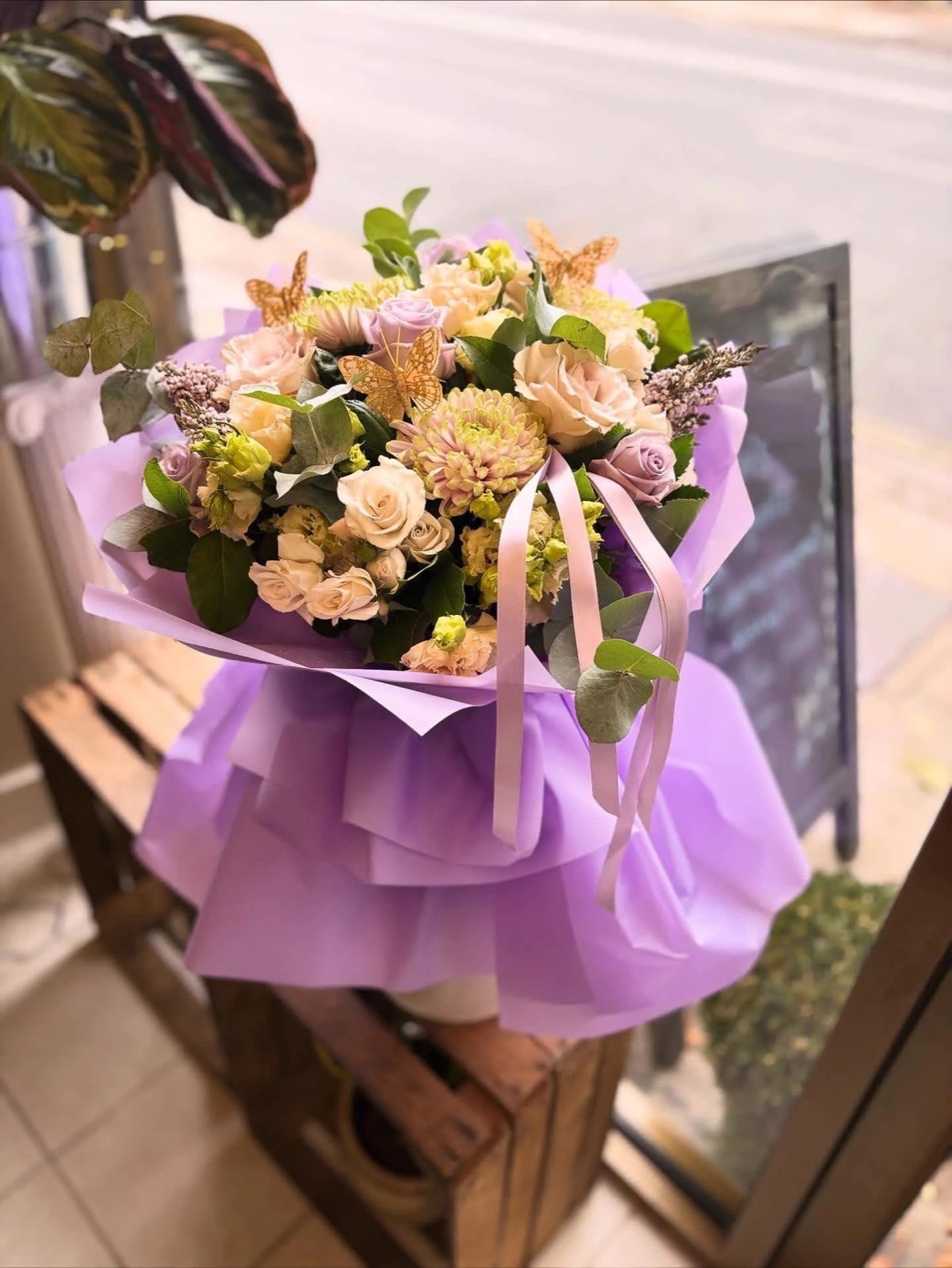 Mixed bouquet in orange wrap with a decorative butterfly